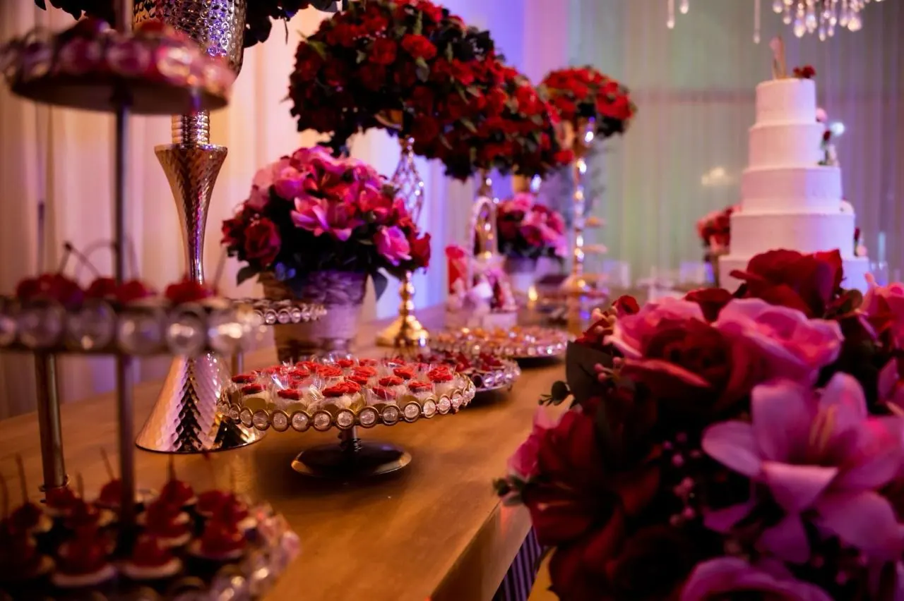 Mesa de doces com flores vermelhas e bolo branco